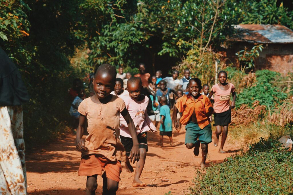 children running and walking on brown sand surrounded with trees during daytime. Photo by: Seth Doyle